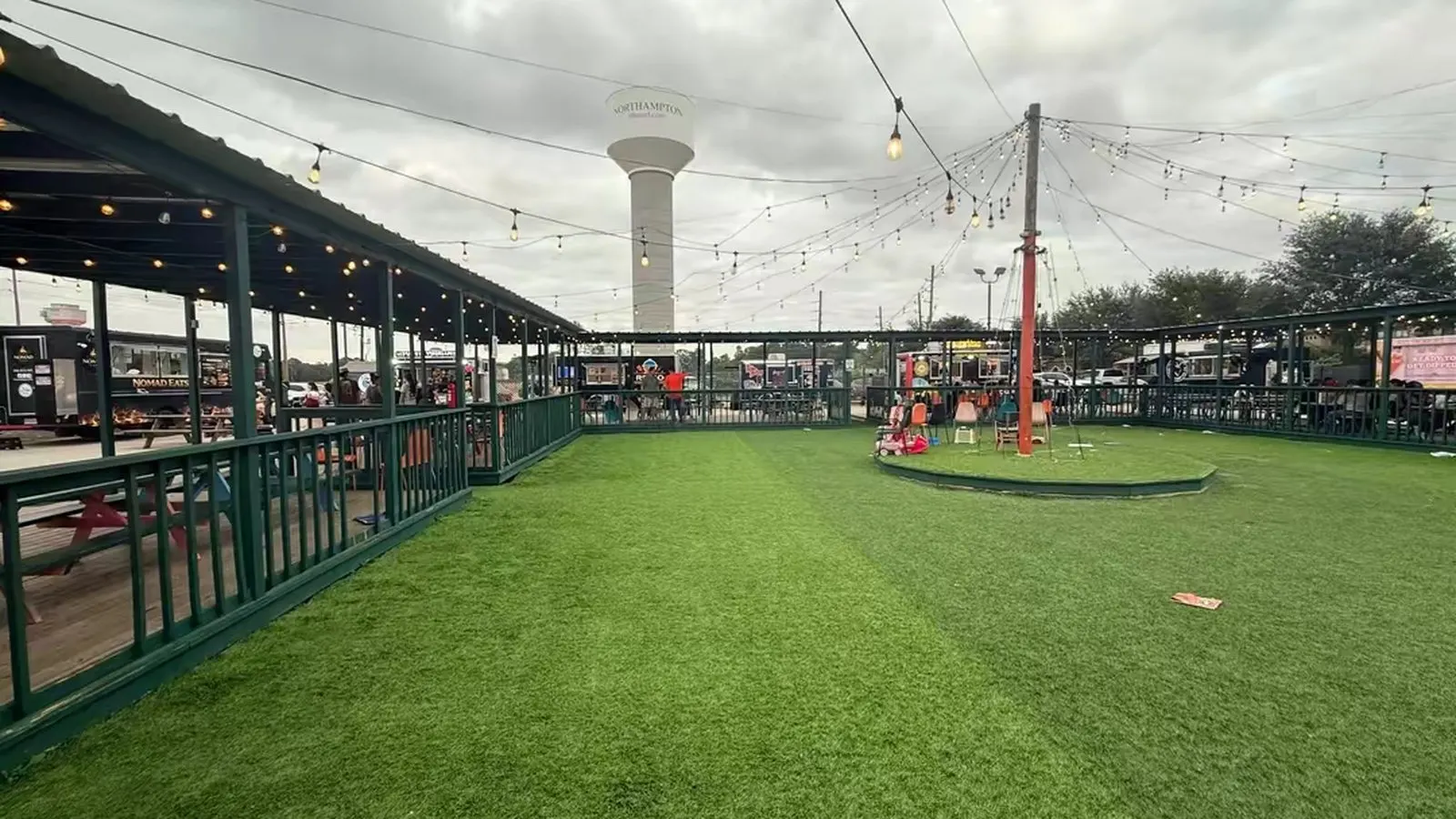 The food truck park at dusk, with the water tower behind the covered seating